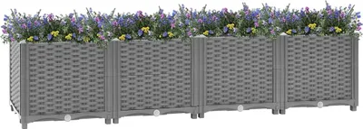 A row of four grey modular raised garden beds filled with purple and yellow flowers.