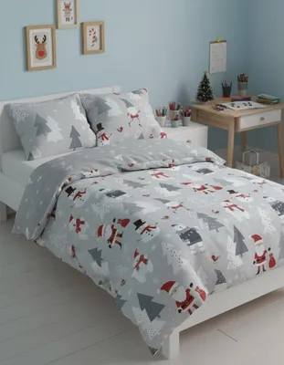 A child's bedroom with a bed made up with Christmas-themed bedding.