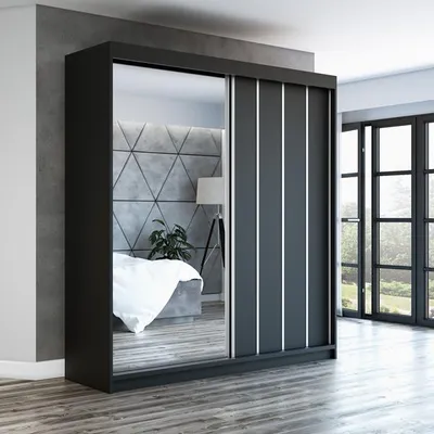 A modern bedroom with a large sliding door wardrobe with a mirrored front.