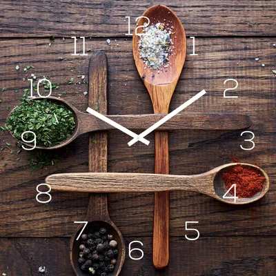 A clock face made of wooden spoons filled with spices and herbs on a wooden background.