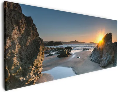 Produktbild von Wallario Premium Leinwandbild Sonnenuntergang hinter einem Felsen am Strand in Größe 50 x 125 cm