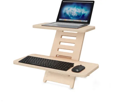 A wooden standing desk converter with a laptop, keyboard, and mouse on it, set against a white background.