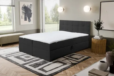 A bedroom scene with a bed, rug, and artwork.