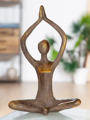 A decorative figurine of a woman in a yoga pose, with hands raised above her head and palms together.