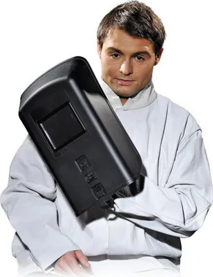 A man wearing a white protective jacket holds a black welding mask.