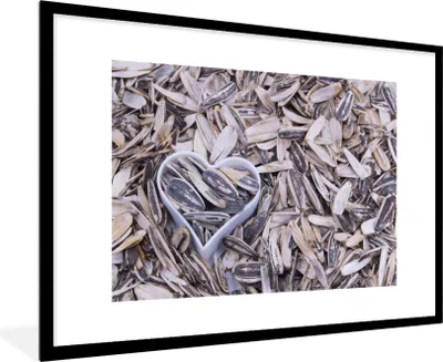 Produktbild von MuchoWow® Gerahmtes Poster Sonnenblumenkerne mit einem herzförmigen Aussehen zwischen den Kernen 90x60 cm - Poster mit Schwarzem Bilderrahmen Wandposter Rahmen Foto Bilder - Wanddekoration - Fotos