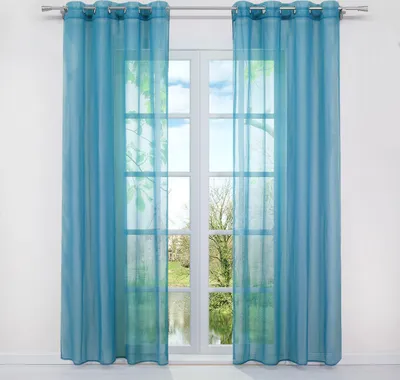 Two blue sheer curtains hanging in front of a window with a view of trees and water.
