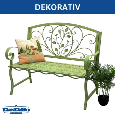 A green metal garden bench with a decorative backrest, a cushion, and a potted plant next to it, set against a white background.