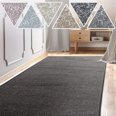 A dark grey rug runner is laid out on a wooden floor in a room with white wainscoting and light grey curtains. Several triangular swatches of different rug colors are displayed above the wainscoting.