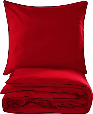 A folded red duvet and a red pillow with black trim, presented on a white background.