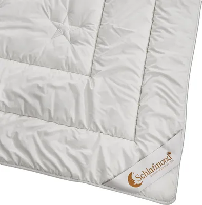 A close-up view of a white duvet with visible stitching and a brand label.
