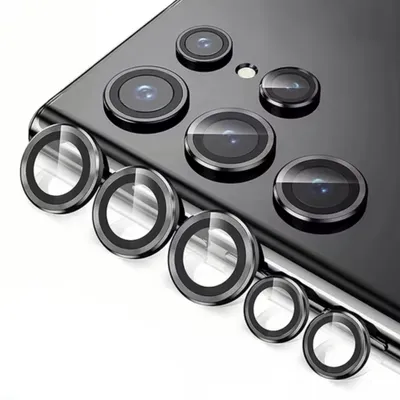 A close-up view of multiple camera lens protectors arranged on a surface, with a portion of a smartphone visible in the background.