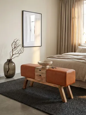 Die Design Sitzbank aus braunem Leder und Mangoholz steht als Blickfang in einem modernen Eingangsbereich auf einem dunklen Teppich, stilvoll dekoriert._#sku_SAFWL6.481#