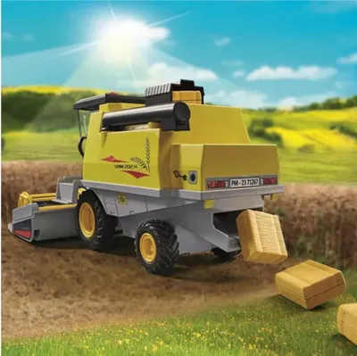 A yellow and gray combine harvester is shown in a field, harvesting wheat and depositing bales of hay.