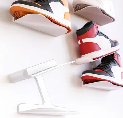 Several pairs of sneakers are displayed on white wall-mounted shelves.