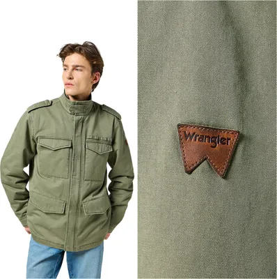A man wearing a green jacket and jeans, with a close-up of the jacket's leather logo.