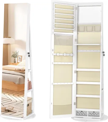A white jewelry cabinet with a full-length mirror is shown open, revealing its interior storage compartments and shelves. The cabinet is placed in a bedroom setting, with a bed and nightstand visible in the reflection of the mirror.