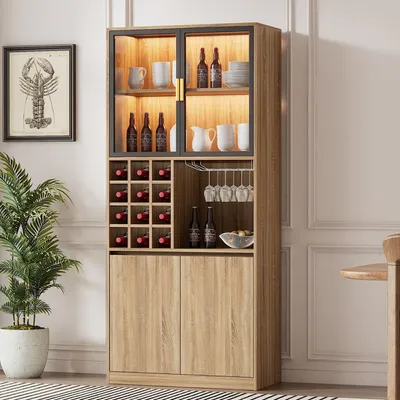 A tall, multi-compartment cabinet with glass doors and interior lighting, designed for storing wine and glassware, placed in a room setting with a plant and a framed picture.