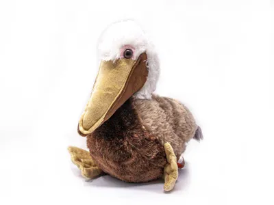 A plush toy pelican is sitting on a white background.