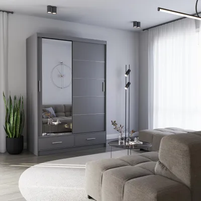 A modern bedroom or living room setting featuring a gray sliding door wardrobe with a mirrored panel, a sofa, a coffee table, and a floor lamp.