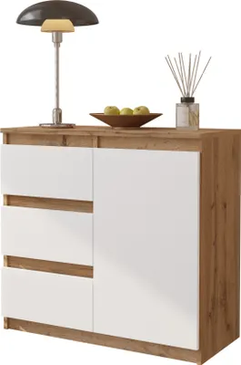 A modern sideboard with white drawers and a wood-grain effect frame, decorated with a lamp, a bowl of apples, and a diffuser.
