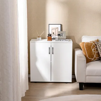 A white storage cabinet with two doors is placed next to a white sofa in a room with light beige walls and a sheer white curtain.
