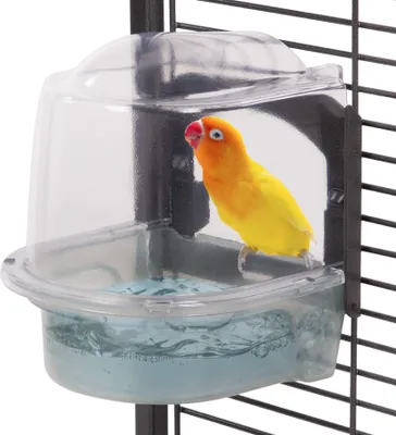 A yellow lovebird is inside a clear plastic bird bath attached to a bird cage.