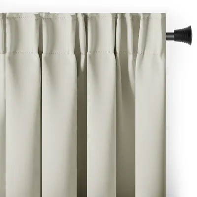 A close-up view of cream-colored blackout curtains hanging from a black curtain rod.