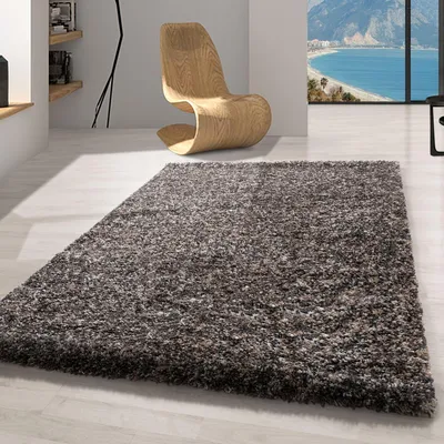 A shaggy rug in a modern living room with a stylish wooden chair and a large window overlooking the ocean.