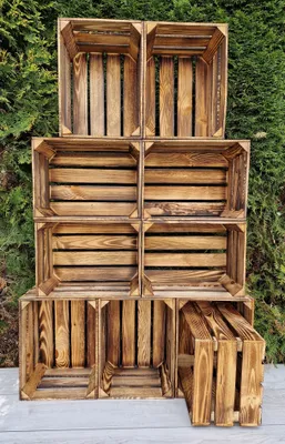 A stack of wooden crates against a green hedge background.