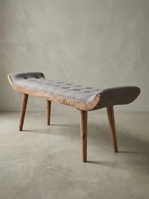 Studioaufnahme einer grauen Sitzbank 125x51x38 cm mit Chesterfield-Steppung und Holzbeinen, freigestellt vor weißem Hintergrund aus einer frontalen 3/4-Ansicht._#sku_BARWL6.013#