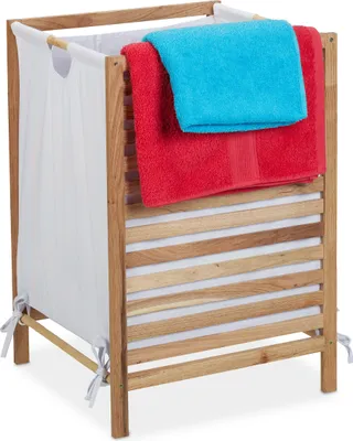 A laundry basket made of wood with a white fabric liner, holding two folded towels.