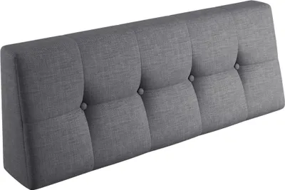 A close-up, angled view of a tufted gray headboard.