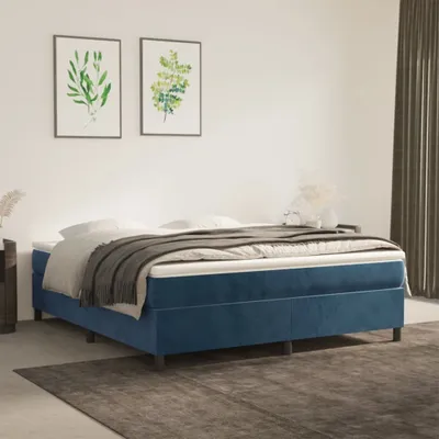A blue upholstered bed with a mattress and gray blanket in a room with artwork on the wall.