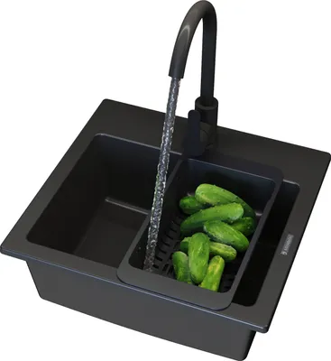 A black kitchen sink with a faucet running water over cucumbers in a colander.