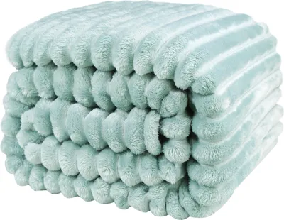 A close-up, studio shot of a light blue, plush blanket folded and stacked.