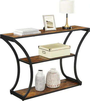 A console table with three shelves, decorated with books, a framed picture, a lamp, a decorative box, and two vases.