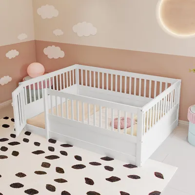 A white wooden crib with a gate, set up in a child's room with cloud-shaped wall decorations and a dalmatian-print rug.