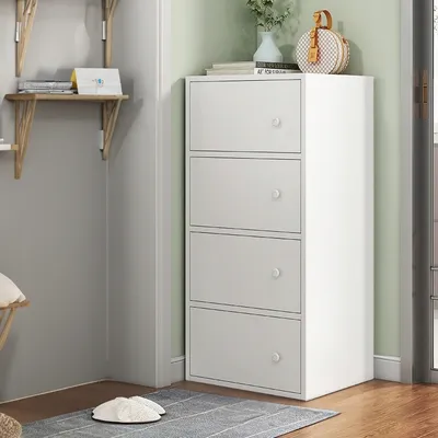A white four-drawer cabinet is positioned in a corner of a room, with shelves on the left wall.