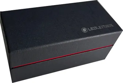 A closed black box with a red stripe and a silver logo.