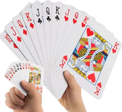 Two hands holding a fan of jumbo playing cards, with a smaller fan of regular-sized playing cards in the foreground.