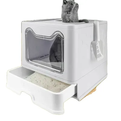 A grey cat is peeking out of a white litter box with a pull-out drawer.