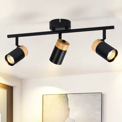 A black track light fixture with three adjustable spotlights, each featuring a wooden accent, mounted on a white ceiling.