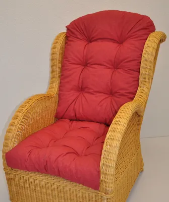 A close-up view of a wicker armchair with red cushions.