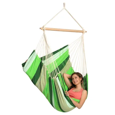 A woman relaxing in a green striped hammock chair.