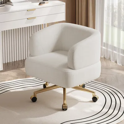 A beige office chair with gold legs and wheels is placed on a rug in front of a white vanity table.