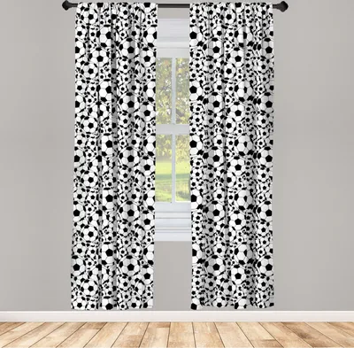 Two curtains with a repeating pattern of soccer balls hang in front of a window.