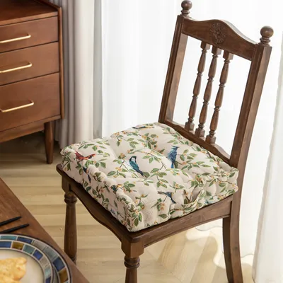 A close-up of a chair with a cushion, placed next to a wooden dresser.