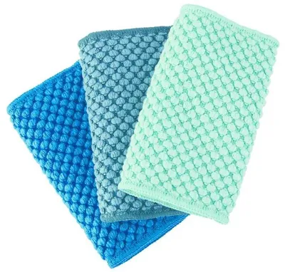Three textured cloths in varying shades of blue and green are arranged diagonally on a white background.