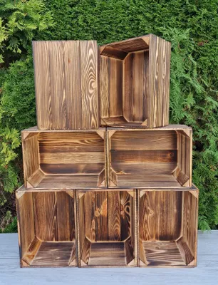 A stack of wooden crates against a green leafy background.